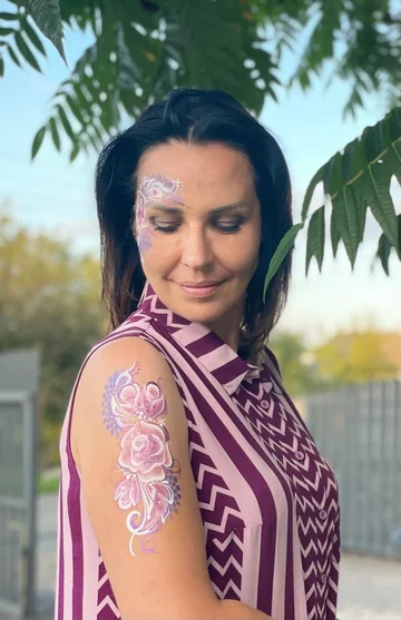 Tati con flores pintadas en el rostro y el brazo