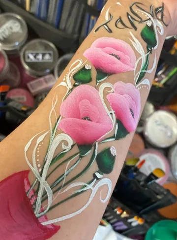 Flores rosas con hojas verdes y adornos blancos pintados en el brazo