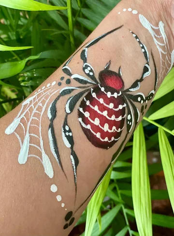 Araña roja y negra con telarañas blancas en el brazo