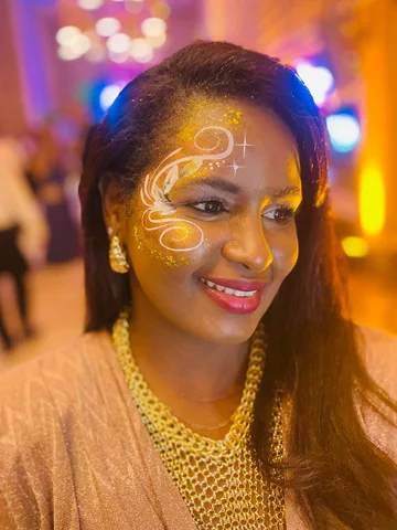Maquillaje dorado con glitter y arabescos blancos