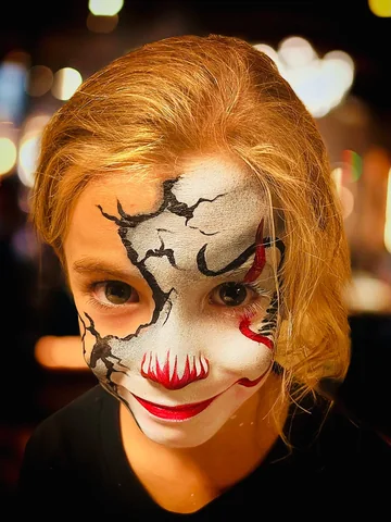 Maquillaje de Halloween blanco con detalles rojos en el rostro de una niña