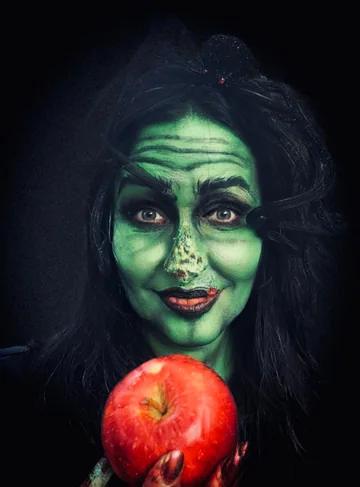 Bruja verde con una manzana roja