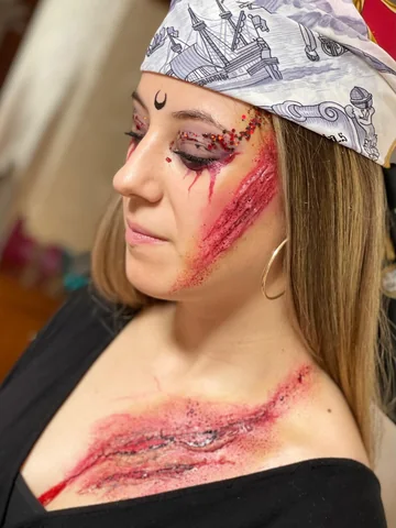 Detalle de maquillaje de Halloween con heridas simuladas y glitter