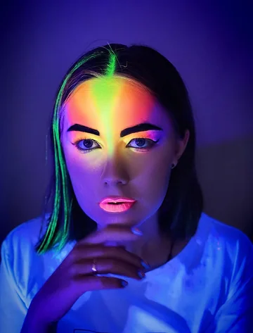 Retrato con maquillaje neón multicolor bajo luz ultravioleta