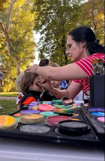 Artista pintando el rostro de un niño en un evento al aire libre