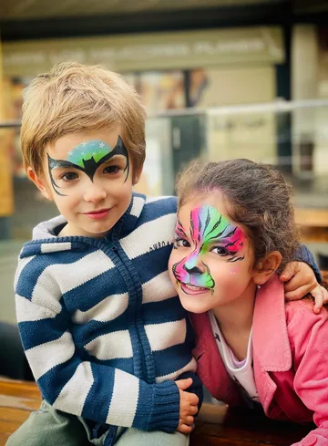 Dos niños con maquillaje de superhéroe y tigre multicolor