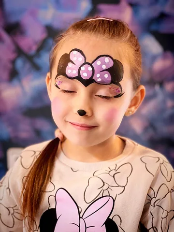 Niña con lazo violeta de Minnie pintado en el rostro