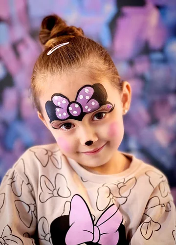 Niña con lazo violeta de Minnie pintado en el rostro