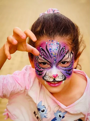 Niña con pintacaras de tigre violeta y glitter