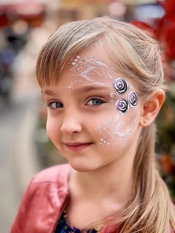 Niña con rosas blancas y detalles violetas pintados en el rostro