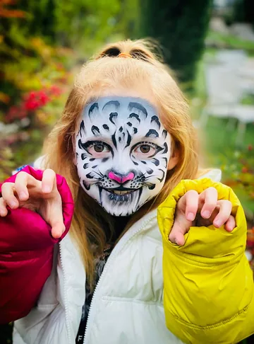 Niña con maquillaje de tigre blanco y nariz rosa